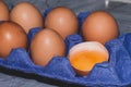 Chicken eggs with one broken fresh raw orange yolk in shell