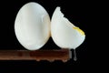 Chicken eggs, one egg is broken in which the yolk is visible and the white flows down on a black background Royalty Free Stock Photo