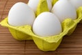 Chicken eggs in a package, isolated on a wooden table, crop