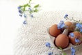 Chicken eggs in a package on a white napkin with forget-me-nots, white background, space for text - the concept of preparing for