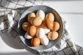 Chicken eggs white and brown color in a gray plate on a checked kitchen towel on a white table. concept farm products.