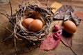 Chicken eggs in a wicker basket in the shape of a bird`s nest, lying on an old wooden surface Royalty Free Stock Photo