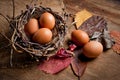 Chicken eggs in a wicker basket in the shape of a bird`s nest, lying on an old wooden surface Royalty Free Stock Photo