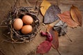 Chicken eggs in a wicker basket in the shape of a bird`s nest, lying on an old wooden surface Royalty Free Stock Photo