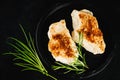 Semi-finished chicken fillets,lightly fried,on a dark background with fresh herbs.Half-finished.Quick cooking at home