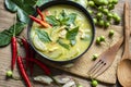 Chicken green curry Thai food on soup bowl with ingredient vegetable herbs and spices pepper chili on wooden table background, Royalty Free Stock Photo