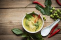 Chicken green curry Thai food on soup bowl with ingredient vegetable herbs and spices pepper chili on wooden table background, Royalty Free Stock Photo