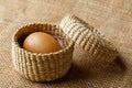 Chicken or hen egg in wicker basket on sackcloth Royalty Free Stock Photo