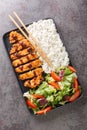 Chicken katsu is a traditional Japanese dish served with rice and vegetables salad closeup in the plate. Vertical top view Royalty Free Stock Photo