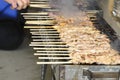 Chicken kebabs on the grill and human fingers