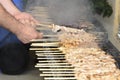 Chicken kebabs on the grill and human hands