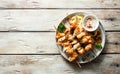 Chicken kebabs on skewers and savory cream sauce on grunge plate on natural wooden table