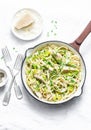 Chicken, leek, linguine pasta carbonara in a frying pan on a light background, top view. Flat lay