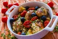 Chicken legs with potatoes, cherry tomatoes and black olives. White baking dish on wooden background Royalty Free Stock Photo