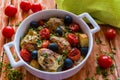 Chicken legs with potatoes, cherry tomatoes and black olives. White baking dish on wooden background Royalty Free Stock Photo