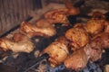 Chicken legs and wings are cooked over a fire in a large stone grill. Delicious food at the campfire. Royalty Free Stock Photo