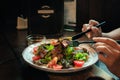 Chicken liver and Fig salad. Women`s hands take a fork and knife warm salad with a dressing of olive oil and Dijon mustard Royalty Free Stock Photo