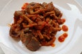 chicken liver, gizzard and chicken intestine cooked with spices, turmeric, and chilies served on a white plate, on white