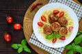 Chicken meat balls, pasta fusilli, tomatoes, basil on a white plate on a wooden tray. Royalty Free Stock Photo