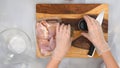 Chicken meat, soy sauce, and seasoning close up on wooden board. Woman cooking sour cream chicken paprika