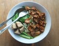 Noodle soup topped with chicken in small slices and mustard greens. Wooden background Royalty Free Stock Photo