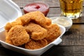 chicken nuggets in a food delivery box with white and red sauce and beer on a brown wooden background. fast food Royalty Free Stock Photo