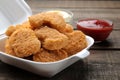 Chicken nuggets in a food delivery box with white and red sauce on a brown wooden background. fast food close-up Royalty Free Stock Photo