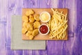 Chicken nuggets, French fries and two cups with ketchup and cheese on the table