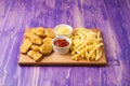 Chicken nuggets, French fries and two cups with ketchup and cheese on the table