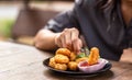 Chicken Nuggets impaled on a fork and Dip sauce. A women eat Nuggets