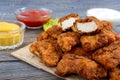 Chicken nuggets. Pieces of deep-fried crispy meat, on paper with different sauces on a wooden table.