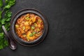 A Chicken Patiala in black bowl on dark slate table top. Murg Patiala is indian cuisine curry dish. Asian food and meal