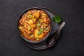 A Chicken Patiala in black bowl on dark slate table top. Murg Patiala is indian cuisine curry dish. Asian food and meal