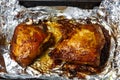 Chicken pieces with a crispy crust in sauce baked in foil on a baking sheet.