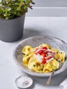 Chicken Ravioli with topping ricotta cheese, tomatoes, herbs, grated parmesan, on a marbre dish light background, traditional