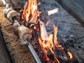 Chicken roasted on spit being grilled over flames Royalty Free Stock Photo