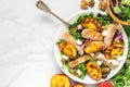 Chicken salad with grilled peach, mixed salad, feta cheese and walnuts in a plate with fork. healthy food. top Royalty Free Stock Photo