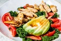 Chicken salad with tomato, avocado and kale in gray bowl. Diet food concept