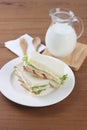 Chicken sandwiches on white dish with milk and wooden fork and spoon. Royalty Free Stock Photo