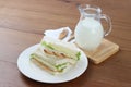 Chicken sandwiches on white dish with milk and wooden fork and spoon. Royalty Free Stock Photo