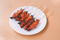 Chicken Satay or Chicken skin satay with red spices on white plate isolated on wooden tables