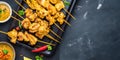 Chicken Satay With Peanut Dipping Sauce on a slate background with copy space