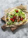 Chicken schnitzel greek gyros with lettuce, tzatziki sauce, roasted tomatoes, cucumbers, olives on a cutting board on a light Royalty Free Stock Photo