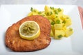 Chicken schitzel on white plate decorated with butter and lemon