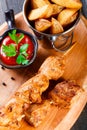 Chicken skewers with sauce and potatoes fries in a bucket on wooden cutting board Royalty Free Stock Photo