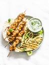 Chicken skewers souvlaki, grilled zucchini, tortillas and tzadziki sauce - delicious greek style lunch on a light background, top