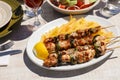 Chicken souvlaki cooked on grill served with french fries, half of lemon in greek tavern. Royalty Free Stock Photo