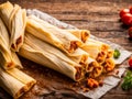 Chicken tamales wrapped in corn husks in a stack on a cutting board