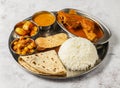 chicken thali set with chicken korma, chanay, plain rice, aloo, shorba and chapati served in dish isolated on background top view