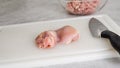 Chicken thighs and kitchen knife close-up on a white plastic cutting board on a kitchen table. Marinated chicken fillet recipe Royalty Free Stock Photo